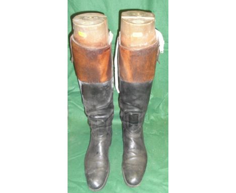 A pair of black and tan hunting boots with wooden trees bearing ivory plaques inscribed "Maxwell, Dover Street, London"
