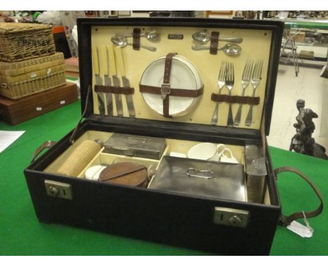 A black cased Brexton's picnic hamper containing four place settings of knife, fork, teaspoon, teacup and saucer and side pla