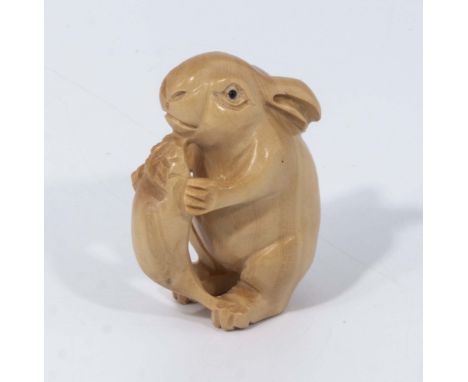 A hand carved hardwood netsuke of rabbit eating carrot