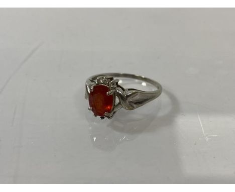 A 9ct gold ring with an oval cut red/orange stone, flanked by diamonds above and below, one diamond missing, size Q/R