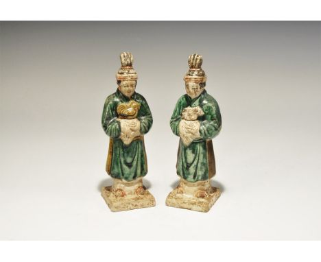 A matched pair of undated archaistic hollow ceramic figurines, each an attendant on a square base in green robe with sash and