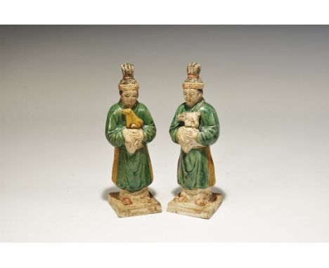 A matched pair of undated archaistic hollow ceramic figurines, each an attendant on a square base in green robe with sash and