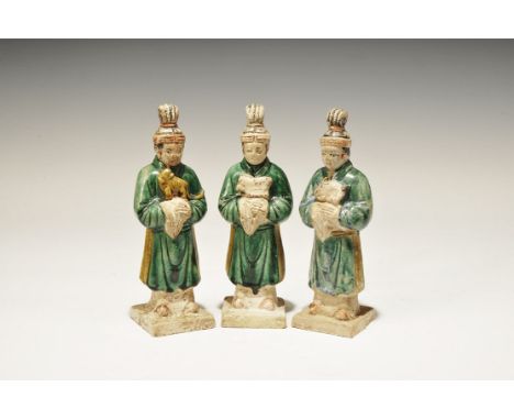 A group of three hollow undated archaistic ceramic figurines, each an attendant on a square base in green robe with sash and 