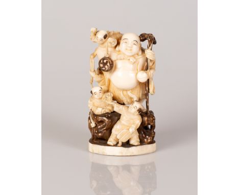 Japanese Bone Statuette in the Figure of Hotei standing on a rock with children playing amongst themselves.   Red hallmark.  