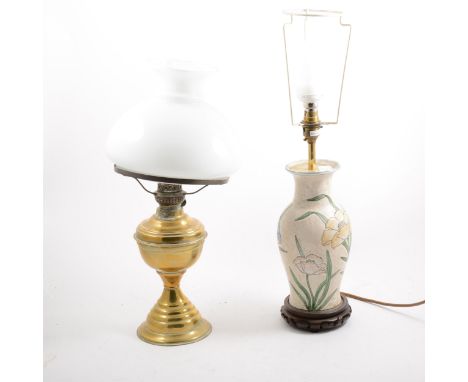 A brass oil lamp with opaque glass shade, and a pottery based table lamp, the baluster form with floral design against a mott