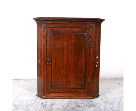 George III oak hanging corner cupboard, cavetto and dentil moulded cornice, panelled door with brass H-hinges, enclosing a sh