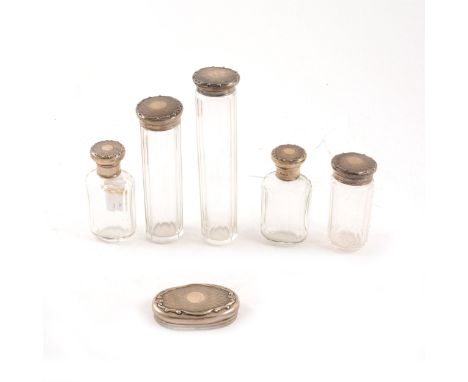 Five silver capped dressing table set bottles and a matching lid by Adie Brothers Ltd, engine-turned with vacant centre circu