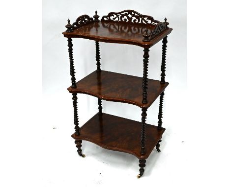 A Victorian walnut three-tier serpentine form whatnot with barley twist supports on ceramic castors 56 cm x 37 cm x 97 cm o/a