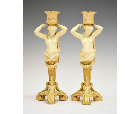 Pair of late Victorian Royal Worcester blush ivory figural candlesticks, each modelled as a semi-naked female term with arms 