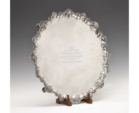 Large Edward VII silver salver, of piecrust form with scroll and shell border, standing upon four scroll feet and having pres