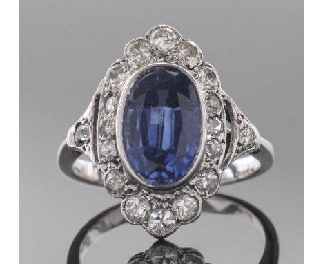 Sapphire and diamond ring, the oval faceted sapphire 10mm x 7mm approx, bezel set within a small diamond set surround, stampe