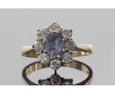 18ct gold sapphire and diamond cluster ring, the pale oval faceted sapphire raised above a small round brilliant cut diamond 