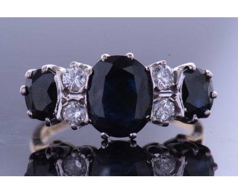 Sapphire and diamond ring featuring three oval cut graduated sapphires, highlighted between with four small brilliant cut dia