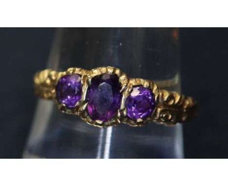 A 9ct gold three stone amethyst ring with engraved shoulders. 2.9g approx. (B.P. 24% incl. VAT)