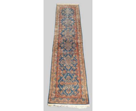 A machine made Persian Hamadan runner, late 20th century, with six floral diamond medallions, on a blue ground, contained by 