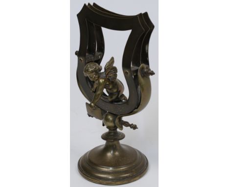A French brass letter rack, 19th century, the rack modelled in a harp shape with three sections, with an attached putti holdi