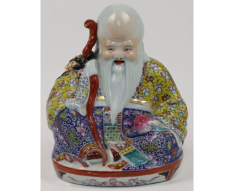 A Chinese porcelain famille rose figure of Shou Lao, 20th century, modelled seated and holding his staff and a fruit, unglaze