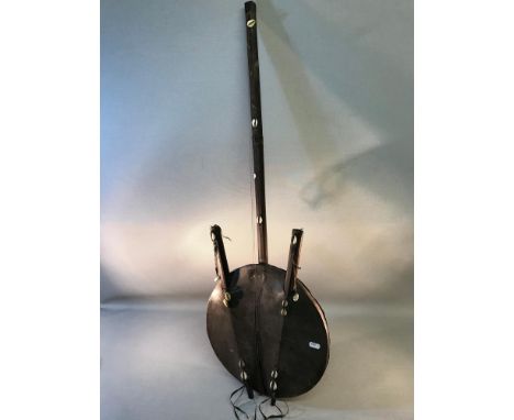 A tribal handmade string instrument, hide and wood material with shell detail 