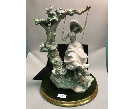 A Lladro figure of a lady swinging on a tree swing, 39cm in height, complete with plinth 