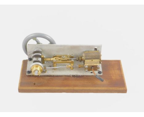 A steel and brass steam engine, raised on a wooden base, 25cm long.