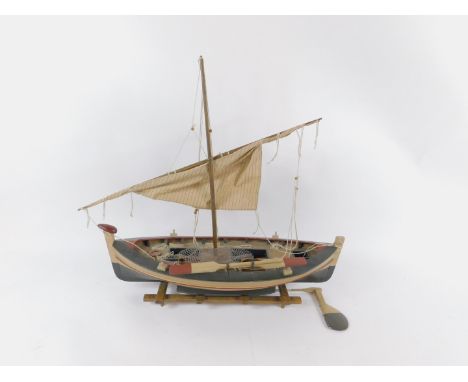 *A Wooden scale model of a Portuguese fishing boat, with rigging nets and oars, raised on a wooden stand, 78cm long.