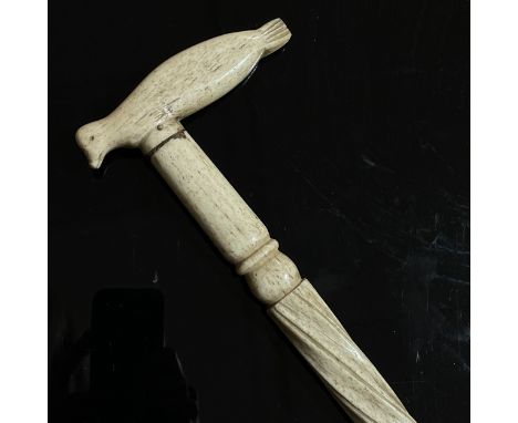 A 19th century narwhal tusk walking stick, with a carved seal handle and twisted stem, length 87cm, handle length 11.5cm