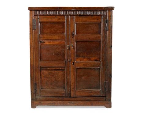 OAK PRESS CUPBOARD LATE 17TH CENTURY with a fluted architectural frieze above a pair of triple panel doors, opening to a hang