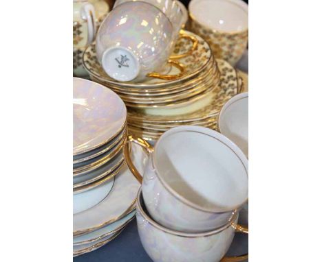 TWO TEA SETS
both with six cups, saucers, side plates and cake plate, one in pearlescent lustreware, the other with gilt foli