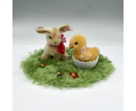 Tan rabbit and yellow chick in a porcelain shell on a green shag circular carpet. Both are sewn to the green base. Steiff tag