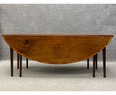 A Georgian mahogany drop flap table having an oval crossbanded top with a central cartouche and a rope inlaid edge raised on 