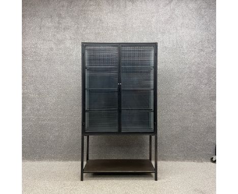 A contemporary industrial style iron cabinet on stand having two laminated mesh glass doors and sides opening on to an interi