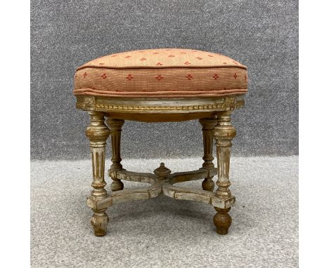 A 19th century Gustavian style stool having a round needlework cushioned top raised on carved and gilt, turned and reeded sup