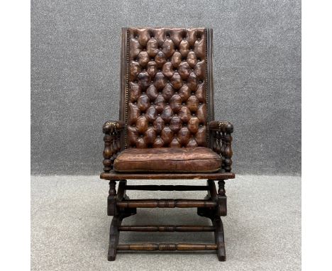 A Victorian mahogany button back rocking chair having a brown leather deep buttoned upholstered back and seat with arms raise