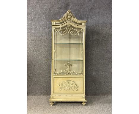 A 19th century French painted vitrine or display cabinet having an arched pediment with a carved floral cresting over a shape