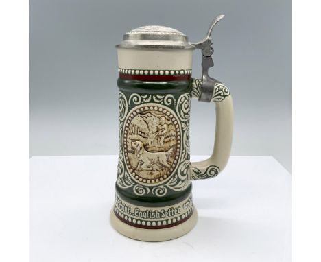A ceramic green and red drinking vessel with a raised pattern depicting two scenes: A hunter with his dog out in the forest, 