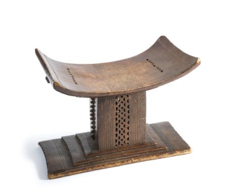 A CARVED AFRICAN STOOL OF ASHANTI TYPE AND A HIDE BUCKET, LATE 19TH/20TH CENTURY the first with characteristic curved seat, p