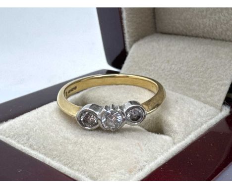An 18ct Gold Three Stone Diamond Ring, the circular brilliant cut centre stone, tension set between collet set circular brill