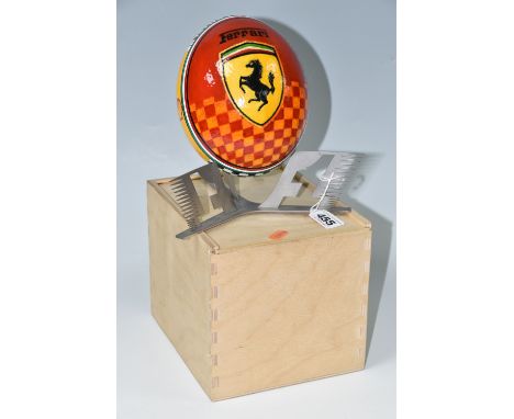 A BOXED HANDPAINTED OSTRICH EGG, decorated with Ferrari emblem and F1 racing car, supported by a metal F1 stand, height inclu