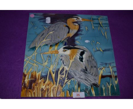 A large ceramic tile of two heron birds signed Pierce