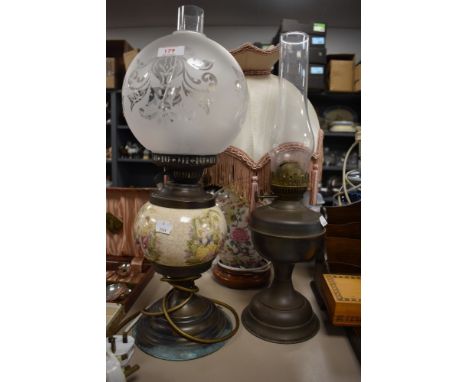 A vintage oil lamp, a desk lamp in the form of an oil lamp and a ceramic lamp with floral pattern and shade.