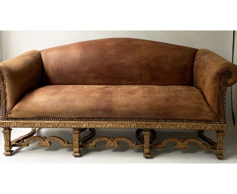 SOFA, early 20th century, natural hide leather, brass studded, with arched back scroll arms and carved stretchered support, 1