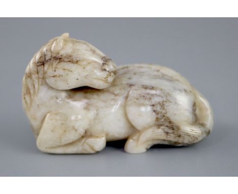 A Chinese white and grey jade figure of a recumbent horse, the stone with some dark brown inclusions, 7.2cm