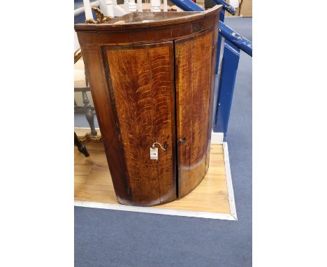 A George III oak bow-fronted hanging corner cupboard, mahogany-banded, width 64cmCONDITION: Perhaps a little faded but essent