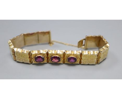 A Victorian engraved yellow metal and three stone garnet set hinged panel bracelet, with safety chain, gross 21.7 grams. appr