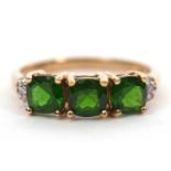 A 9ct diopside and diamond ring, the square mixed cut diospsides with three diamond highlights to