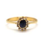 A sapphire and diamond cluster ring, the central oval sapphire surrounded by small round diamonds,