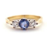 An 18ct sapphire and diamond ring, the central pale blue sapphire set to either side with a round