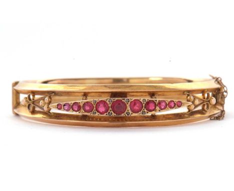 A 9ct ruby bangle, the hinged bangle set with a central marquise shape panel with graduated round rubies, the whole set withi