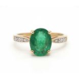 A 9ct emerald ring, the oval emerald, approx. 9mm long, in a four claw mount, with diamond