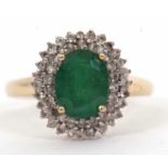 A 9ct emerald and diamond cluster ring, the oval emerald, approx. 9mm long, surrounded by two rows